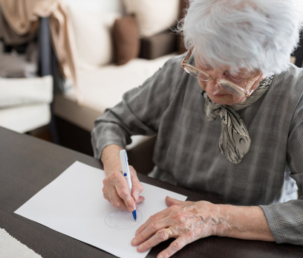 Senior woman writing at a desk.