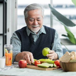 Asian elder senior male vlog teach cooking on mobile phone. Male old man vlogs, Old chef records a video tutorial on his phone about preparing heathy salad and infused water at home